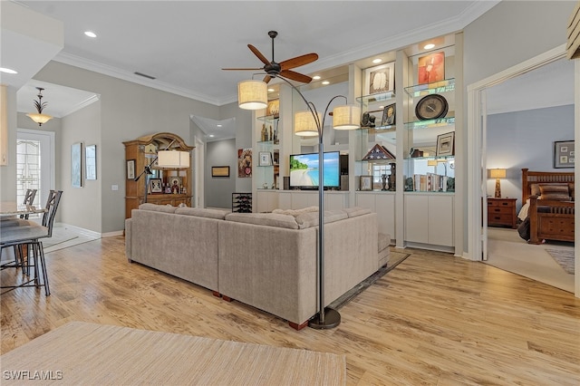 living room with light hardwood / wood-style floors, ceiling fan, and crown molding