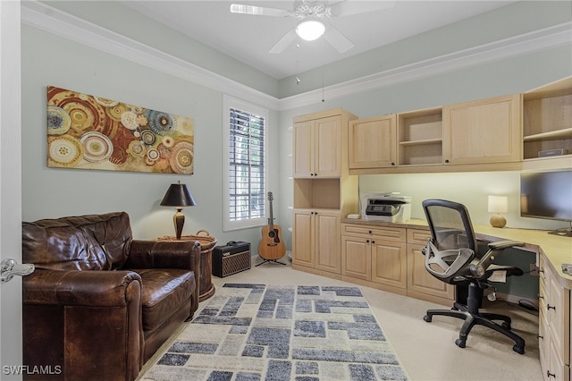 office featuring built in desk, light colored carpet, ceiling fan, and ornamental molding