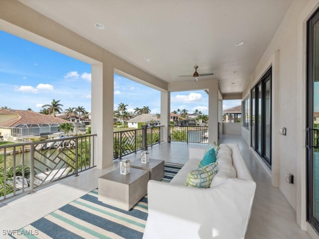 view of patio featuring outdoor lounge area, ceiling fan, a water view, and a balcony