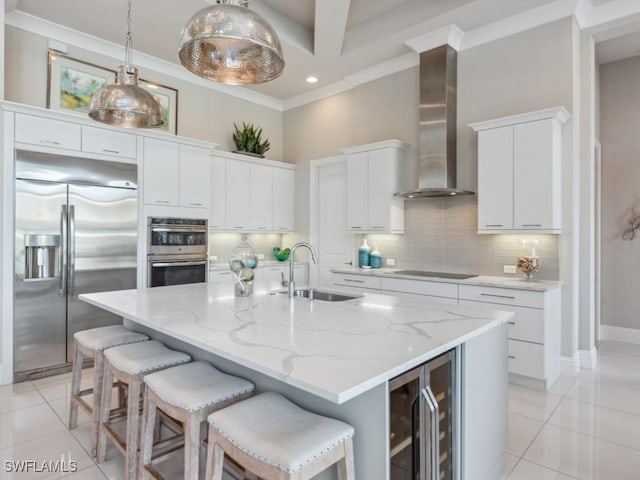 kitchen featuring sink, wall chimney exhaust hood, an island with sink, appliances with stainless steel finishes, and beverage cooler