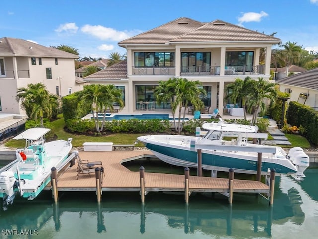 rear view of house featuring a patio, a water view, a balcony, and a swimming pool