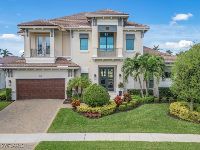 view of front of property featuring a front lawn, french doors, a balcony, and a garage