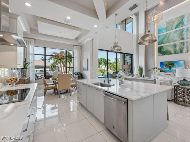 kitchen featuring sink, wall chimney exhaust hood, stainless steel dishwasher, an island with sink, and pendant lighting