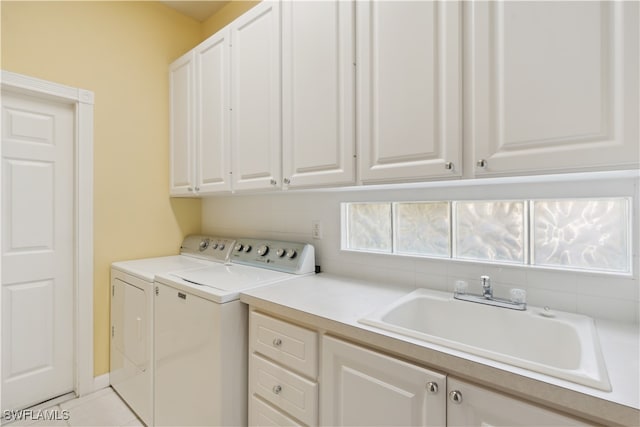 clothes washing area featuring cabinets, sink, washing machine and dryer, and light tile patterned floors