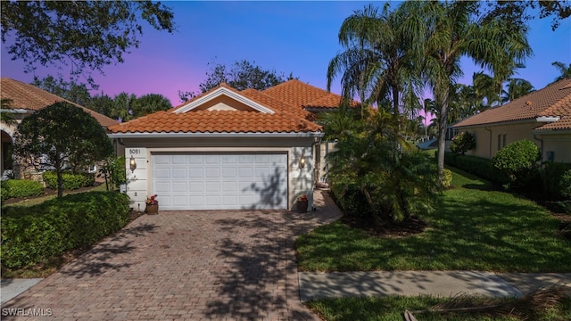 mediterranean / spanish house with a garage and a lawn