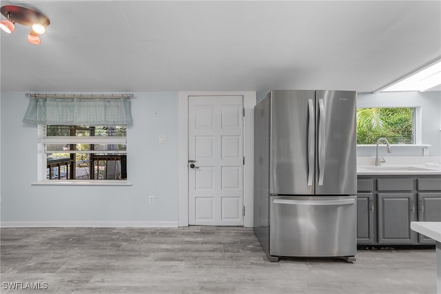 kitchen with stainless steel fridge, light hardwood / wood-style flooring, gray cabinetry, and sink