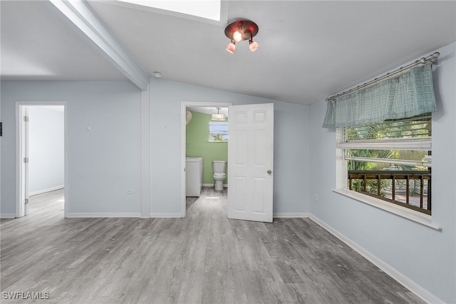 spare room with lofted ceiling with beams and light hardwood / wood-style floors