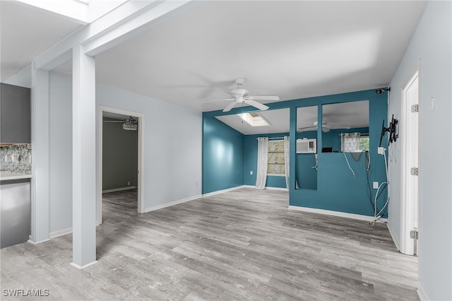 unfurnished living room with a wall mounted air conditioner, ceiling fan, and light hardwood / wood-style flooring