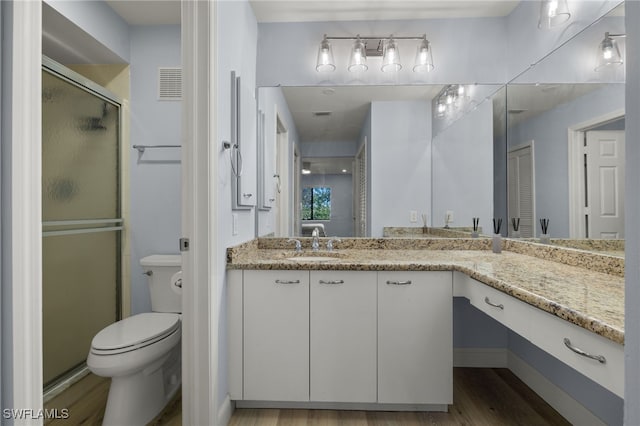 bathroom with vanity, toilet, an enclosed shower, and wood-type flooring