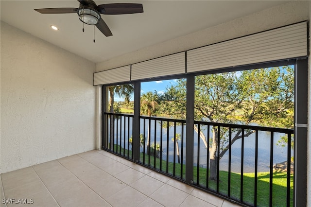 unfurnished sunroom with ceiling fan and a water view