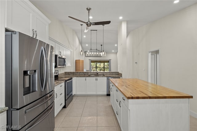 kitchen with appliances with stainless steel finishes, butcher block countertops, sink, white cabinets, and kitchen peninsula