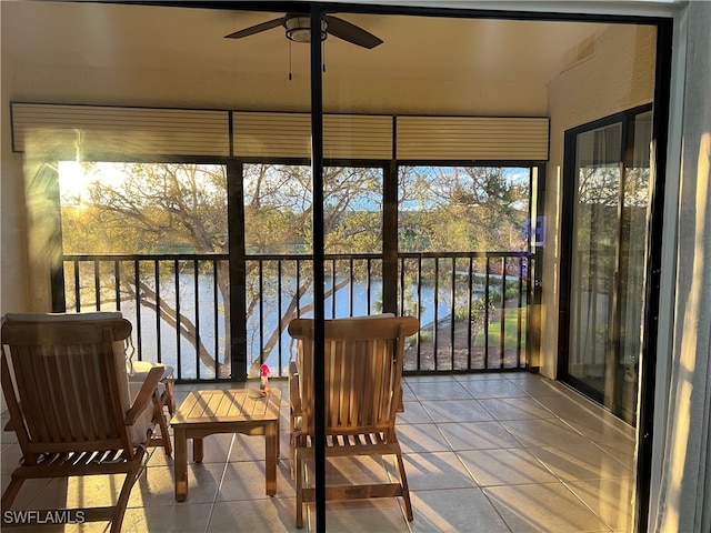 sunroom with a water view and ceiling fan