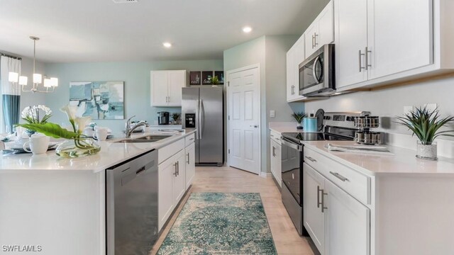 kitchen featuring sink, pendant lighting, stainless steel appliances, light hardwood / wood-style floors, and white cabinets