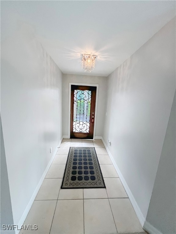 entryway with light tile patterned floors and an inviting chandelier