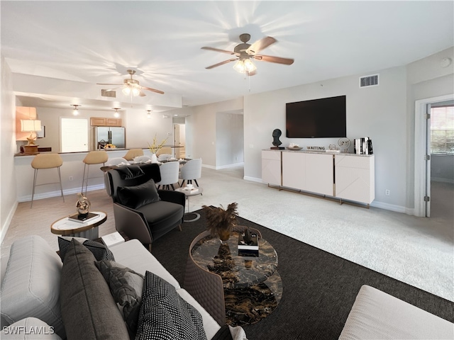 carpeted living room with ceiling fan