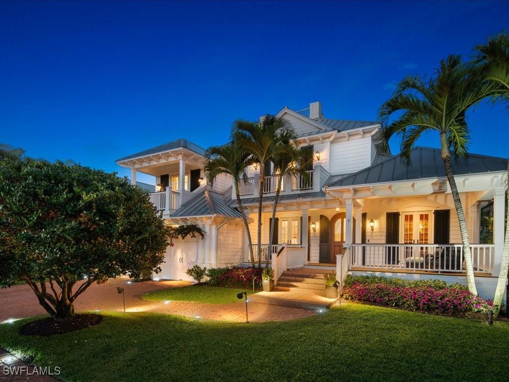 view of front of property featuring a porch, a balcony, a front yard, and french doors