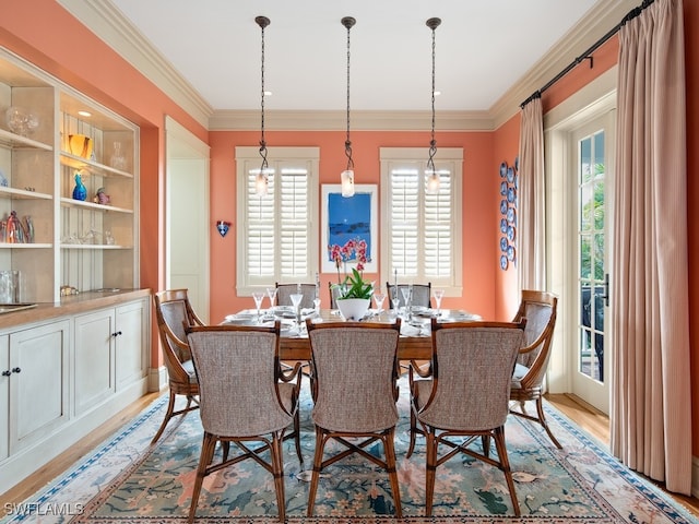 dining area featuring light wood-type flooring, crown molding, and a healthy amount of sunlight