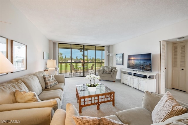 living room with floor to ceiling windows, light carpet, and a textured ceiling