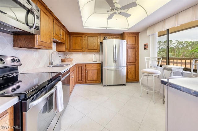 kitchen with decorative backsplash, appliances with stainless steel finishes, ceiling fan, sink, and light tile patterned flooring