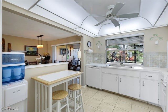 kitchen with white dishwasher, a kitchen breakfast bar, pendant lighting, sink, and white cabinetry