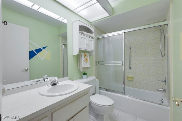 full bathroom featuring shower / bath combination with glass door, tile patterned flooring, vanity, and toilet