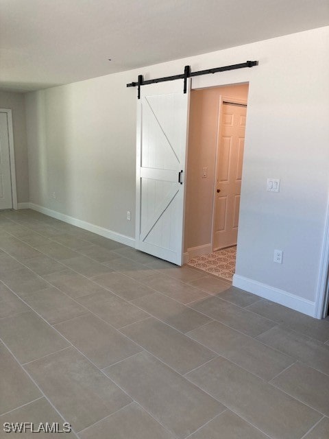 tiled spare room featuring a barn door