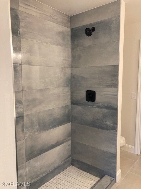 bathroom with a tile shower, tile patterned floors, and toilet