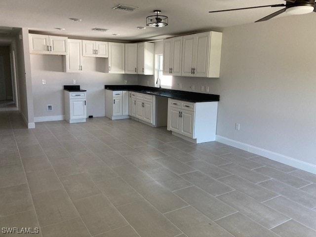 kitchen featuring ceiling fan, white cabinetry, sink, and light tile patterned floors