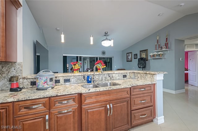 kitchen with pendant lighting, sink, vaulted ceiling, decorative backsplash, and light stone counters