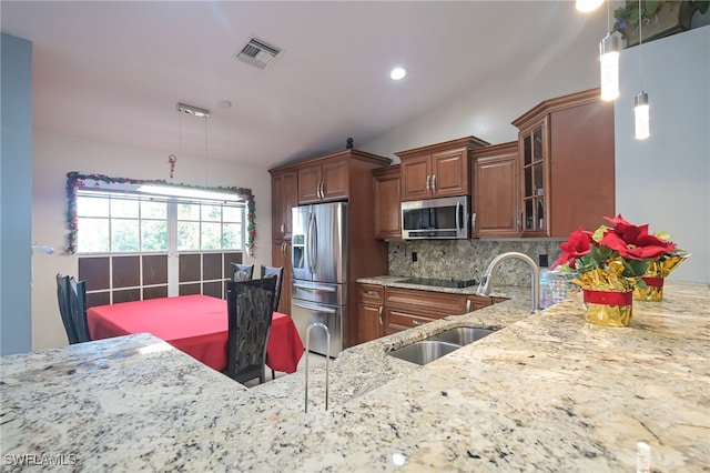 kitchen featuring light stone countertops, sink, stainless steel appliances, tasteful backsplash, and pendant lighting