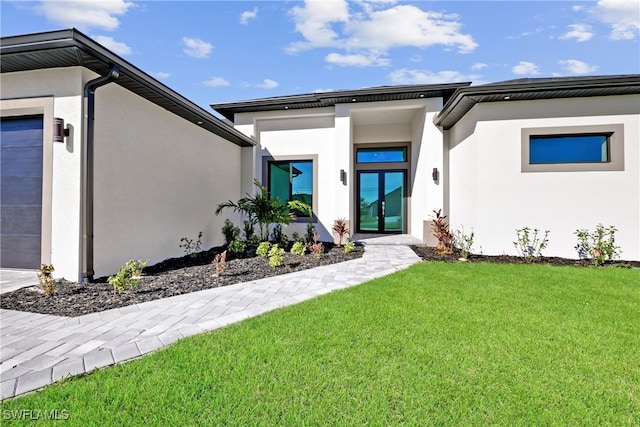 view of exterior entry with a garage, a yard, and french doors