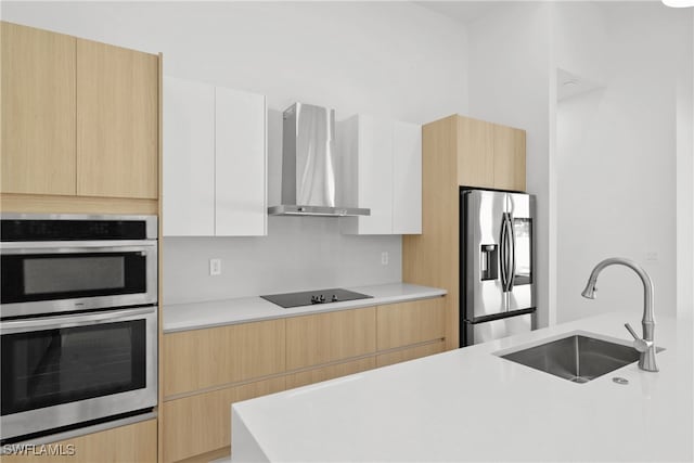 kitchen with sink, white cabinets, stainless steel appliances, and wall chimney range hood