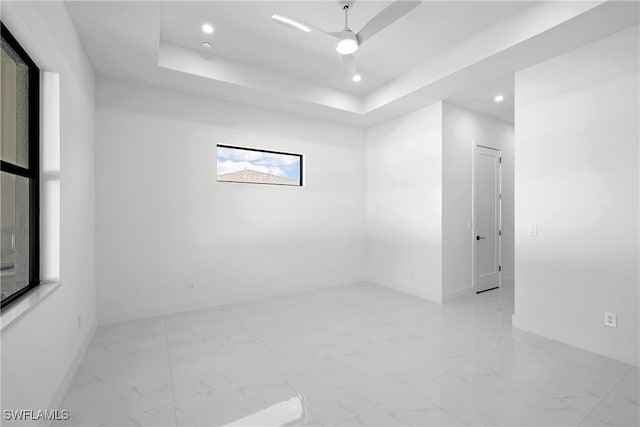 unfurnished room featuring a raised ceiling and ceiling fan