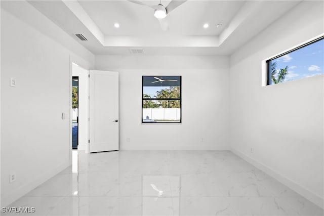 spare room featuring ceiling fan and a raised ceiling