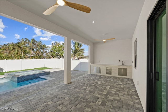 view of patio / terrace with ceiling fan, sink, a pool with hot tub, and exterior kitchen