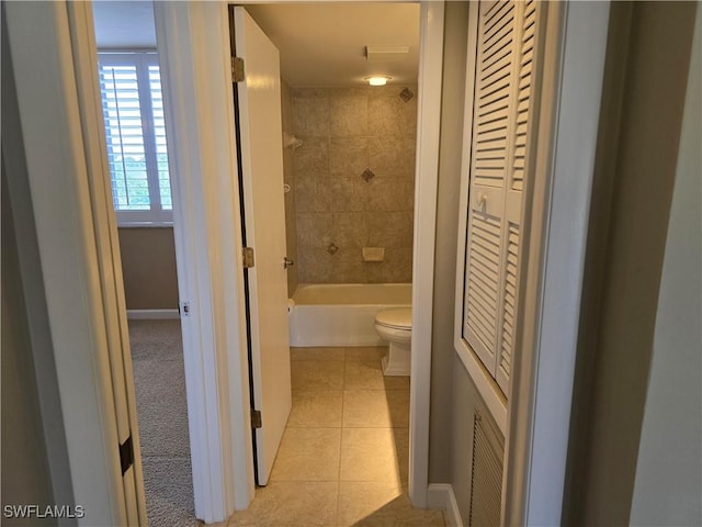 bathroom featuring tiled shower / bath, tile patterned floors, and toilet