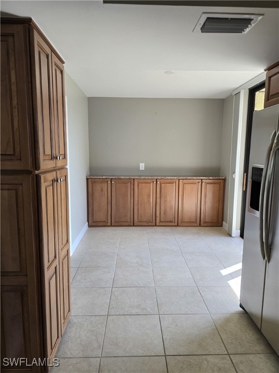 interior space with light tile patterned floors and stainless steel fridge