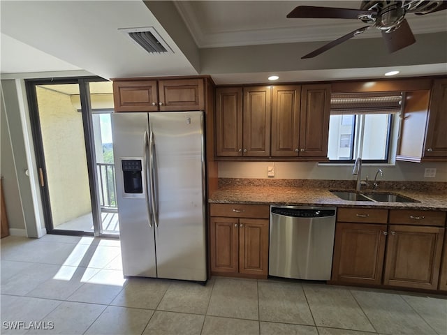 kitchen with sink, crown molding, dark stone countertops, stainless steel appliances, and light tile patterned flooring