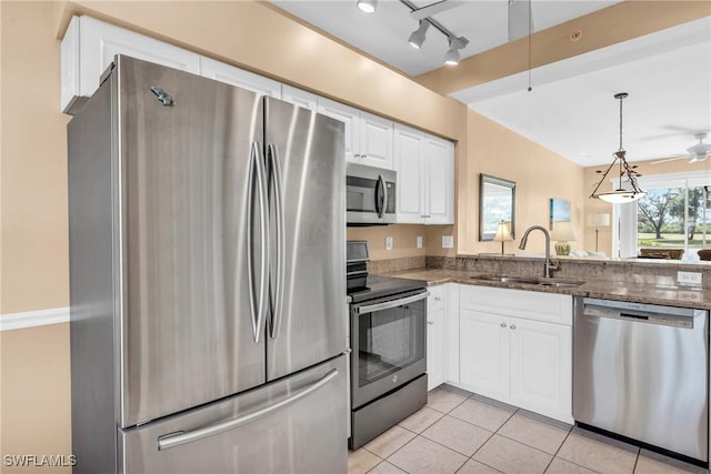 kitchen with dark stone counters, stainless steel appliances, a sink, and light tile patterned flooring