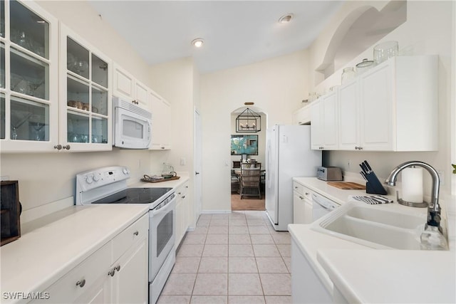 kitchen featuring vaulted ceiling, light tile patterned floors, white cabinets, and white appliances