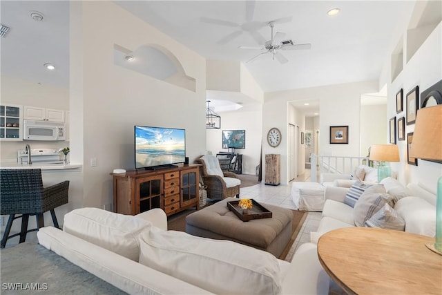 living room featuring ceiling fan with notable chandelier and high vaulted ceiling