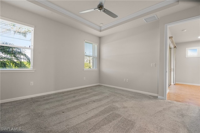 carpeted empty room featuring ceiling fan, crown molding, and a raised ceiling