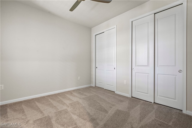 unfurnished bedroom featuring ceiling fan, two closets, and carpet flooring