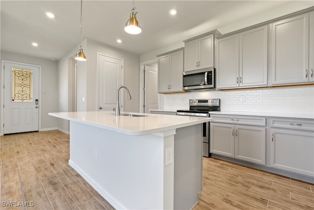 kitchen featuring sink, appliances with stainless steel finishes, and a center island with sink