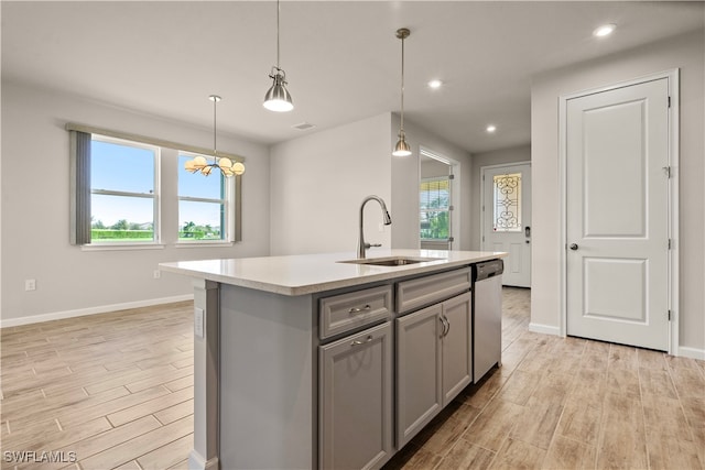 kitchen with decorative light fixtures, a kitchen island with sink, dishwasher, a chandelier, and sink