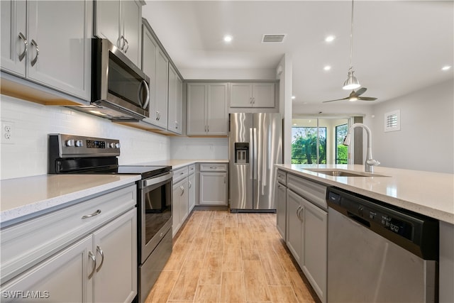 kitchen with decorative light fixtures, stainless steel appliances, sink, ceiling fan, and gray cabinetry