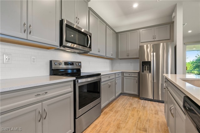 kitchen featuring appliances with stainless steel finishes, gray cabinetry, and backsplash