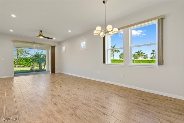 unfurnished room featuring a wealth of natural light and ceiling fan with notable chandelier