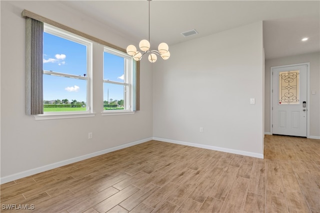 unfurnished room with a notable chandelier and light hardwood / wood-style floors