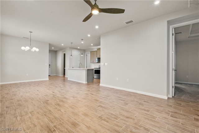 unfurnished living room featuring sink and ceiling fan with notable chandelier